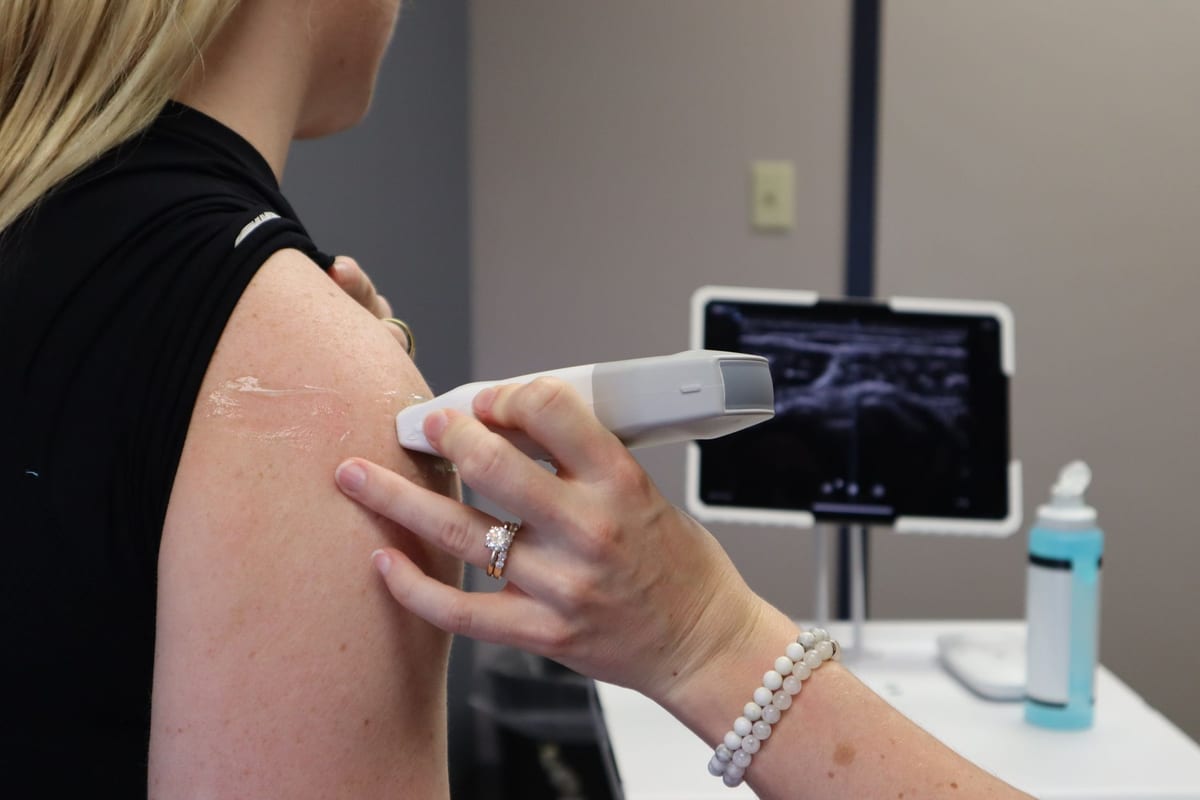 A handheld applicator being used on a patient's shoulder